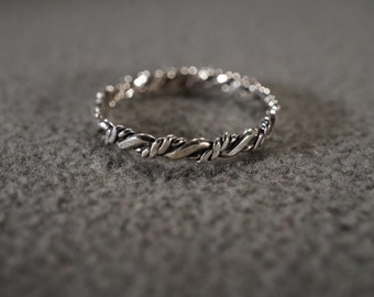 May include: A silver ring with a twisted design. The ring is made of a smooth, shiny metal and has a simple, elegant look.