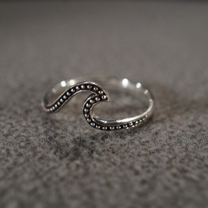 May include: A silver ring with a wave design. The wave is made of small beads and is a simple, elegant design.