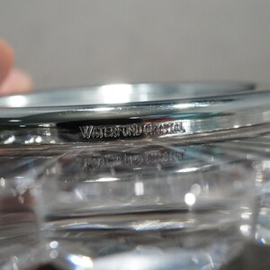 May include: Close-up of a silver-colored, round, crystal bowl with the words "Waterford Crystal" engraved on the rim.