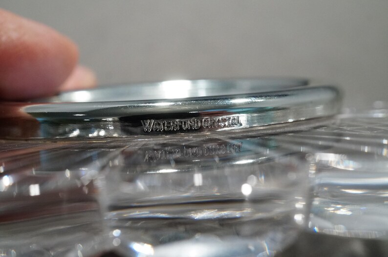May include: Close-up of a silver-colored, round, crystal bowl with the words "Waterford Crystal" engraved on the rim.