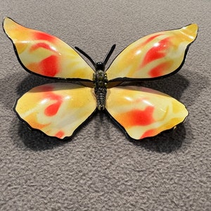 May include: A yellow and red butterfly brooch with black outlining and rhinestones in the center.