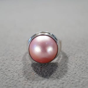 May include: A silver ring with a pink pearl set in a bezel setting.