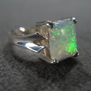 May include: A silver ring with a large, rectangular, green and white opal gemstone.