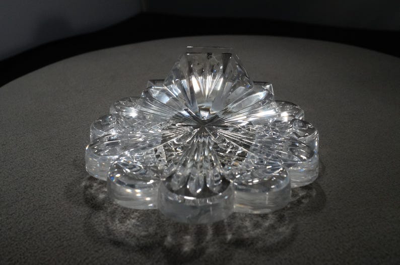 May include: A clear glass flower-shaped dish with a raised center and intricate cut-glass details.