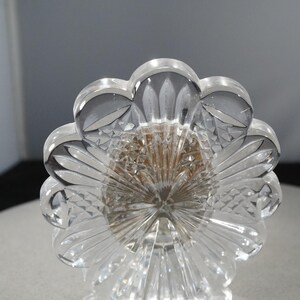 May include: A clear glass picture frame with a flower-shaped design and a crystal base. The frame is decorated with intricate cutouts.