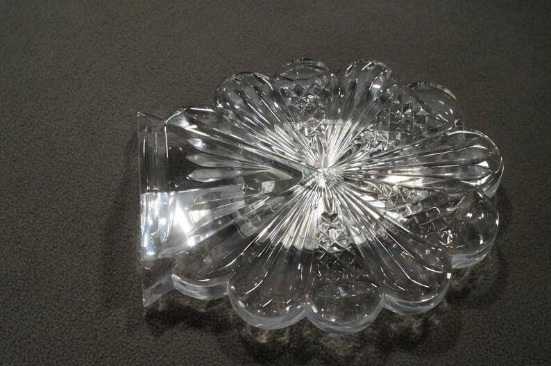 May include: A clear glass decorative dish with a flower-like design. The dish has a scalloped edge and a raised center.