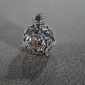 May include: Silver charm with a round, openwork design featuring musical notes and swirls. The charm has a loop at the top for attaching to a necklace or bracelet.