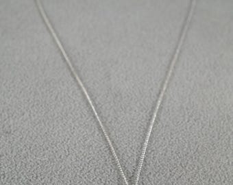 May include: A silver chain necklace with a teardrop-shaped blue gemstone pendant.