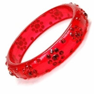 May include: Red plastic bangle bracelet with clear rhinestones in a floral pattern.