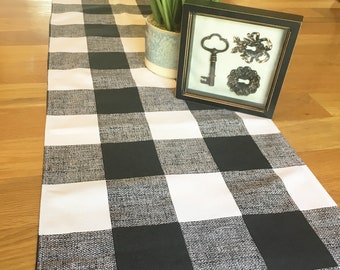 Puede incluir: Un camino de mesa a cuadros blanco y negro con una imagen enmarcada de llaves antiguas y una planta en maceta en el fondo.
