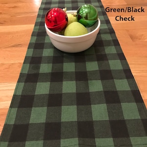 May include: Green and black checkered table runner with a white bowl and Christmas ornaments on top. Green/Black Check.