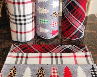 May include: Three fabric rolls and three matching flat fabric pieces featuring patterns of white, black, and red plaid, and a grey background with various Christmas tree designs including leopard print, red plaid, and green checkered patterns.