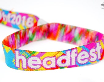 May include: A colorful wristband with the text "headfest" and "#hf2018" printed on it. The wristband is made of woven fabric and has a metal clasp.