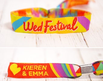 May include: A colorful wristband with the text "Wed Festival" in red lettering. The wristband is yellow with a rainbow pattern. A second wristband is red with a heart and the text "Kieren & Emma" in yellow lettering.