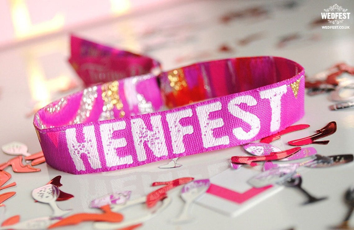 May include: A pink wristband with the word "HENFEST" printed in white letters. The wristband is surrounded by confetti.