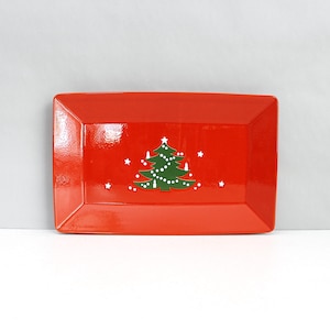 May include: A rectangular ceramic serving platter in a vibrant red finish. The center of the platter features a green Christmas tree graphic decorated with white dots and stars, creating a festive design on the glossy, smooth surface of the dish.