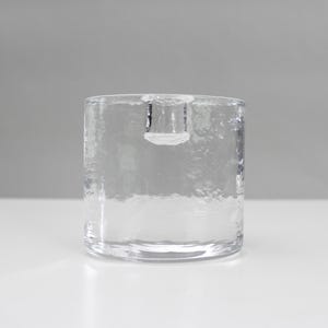 Puede incluir: Un portavelas de vidrio transparente con una superficie texturizada.