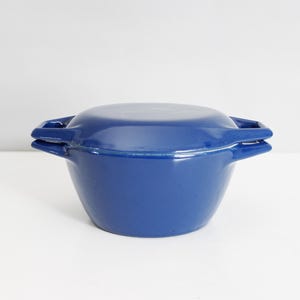 May include: A blue enameled cast iron casserole dish with a lid and two handles.