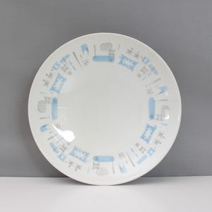 May include: White ceramic plate with a light blue and gray geometric pattern around the rim. The plate has a simple, clean design, suitable for serving food. The plate is round.