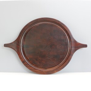 May include: A round wooden serving tray with two handles. The tray is made of dark wood with a natural grain pattern.