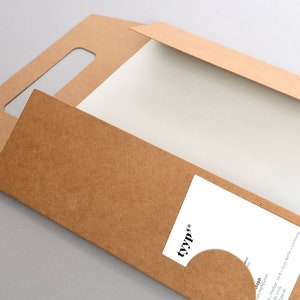 Peut inclure: Une enveloppe en papier kraft avec une poign&eacute;e d&eacute;coup&eacute;e et une carte blanche &agrave; l'int&eacute;rieur. La carte porte un logo qui dit "tyyp." et un petit cercle avec une texture de papier kraft.