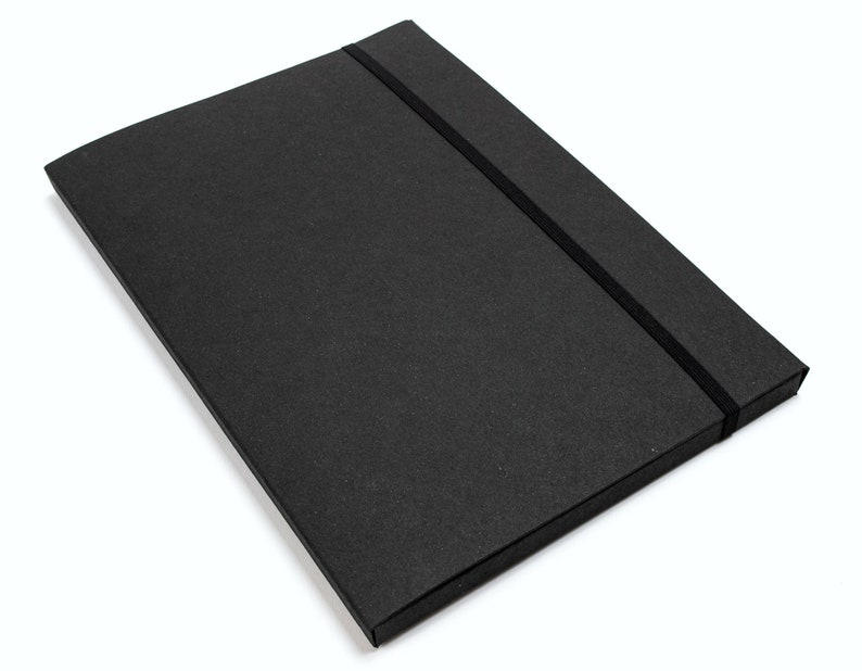 以下が含まれることがあります： 黒色の長方形の箱で、表面はざらざらしており、黒色のゴムバンドで留められています。箱は閉じられており、丈夫な素材で作られているようです。背景は白です。