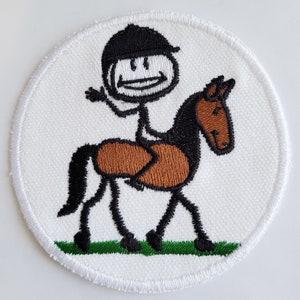 May include: A white embroidered patch with a stick figure riding a brown and black horse. The stick figure is wearing a black helmet. The horse is standing on a green patch of grass.