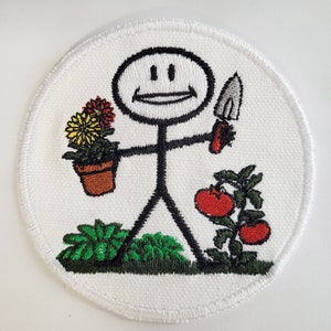 May include: Embroidered patch of a stick figure holding a gardening tool and a potted plant. The stick figure is smiling and has a red, yellow, and green flower in the pot. The patch is white with green grass and red tomatoes.