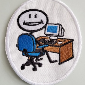May include: White embroidered patch with a stick figure sitting at a desk with a computer, a blue chair, and a brown desk. The stick figure has a smiling face.