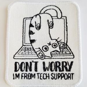 May include: A white embroidered patch featuring a black line drawing of a cat hanging upside down from a laptop. The text "DON'T WORRY I'M FROM TECH SUPPORT" is below the image.