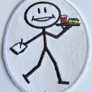 May include: An oval-shaped embroidered patch featuring a black stick figure on a white background. The figure is smiling, holding a black tray with a red drink and a green food item in one hand, and a white notepad with a black pen in the other.