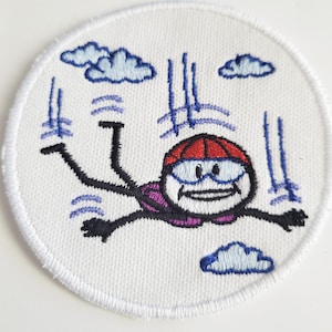 May include: Embroidered patch featuring a stick figure skydiving with a red helmet and goggles, surrounded by clouds and blue lines representing wind.