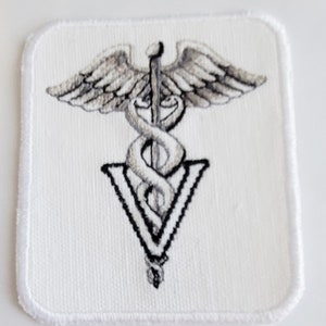 May include: White embroidered patch featuring a grey caduceus symbol and the letters "V" in a triangular shape.