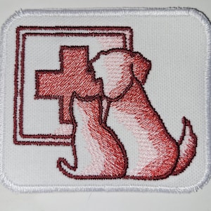 May include: White embroidered patch with a red cross and two red dogs. The patch is for a veterinary clinic or animal hospital.