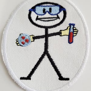 Pode incluir: Etiqueta branca bordada com uma figura de pau que usa óculos azuis, segurando um tubo de ensaio com líquido vermelho e um objeto azul e vermelho.