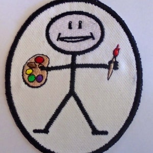 May include: A white oval-shaped patch with a black outline. A stick figure with a smiling face holds a paintbrush and a brown paint palette with red, orange, yellow, green, and purple paint.