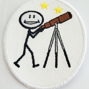 Może przedstawiać: Biała naszywka haftowana z figurką patyczaka trzymającego teleskop i patrzącego w górę na dwie żółte gwiazdy.
