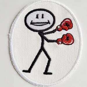 May include: White embroidered patch featuring a stick figure wearing red boxing gloves and smiling.
