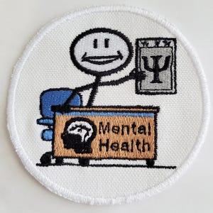May include: White embroidered patch featuring a stick figure therapist seated at a desk with the words "Mental Health" inscribed on it. The therapist is holding a notepad with a psychology symbol.