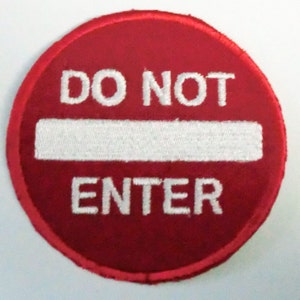 Puede incluir: Un parche circular rojo con texto bordado en blanco que dice "DO NOT ENTER".