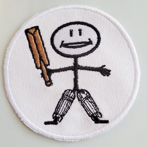 Könnte beinhalten: Weißer gestickter Aufnäher mit einer Strichmännchenfigur, die einen braunen Schläger hält und schwarze und weiße Beinschoner trägt. Die Strichmännchenfigur hat ein lächelndes Gesicht.