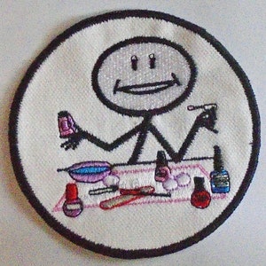 May include: A white embroidered patch featuring a stick figure holding a bottle of nail polish and a nail file. The stick figure is smiling and has two eyes. The patch is surrounded by a black border.