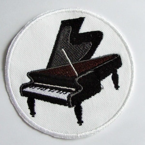 Pode incluir: Patch bordado com um piano de cauda preto com uma placa de som castanha e teclas brancas, sobre um fundo circular branco. O patch tem uma borda branca, adequado para costurar. Para os amantes da música.