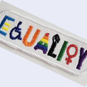 May include: White embroidered patch with the word "EQUALITY" in rainbow colors. The letters are decorated with symbols representing different groups, including a rainbow flag, a peace sign, a wheelchair symbol, a fist, and a female symbol.