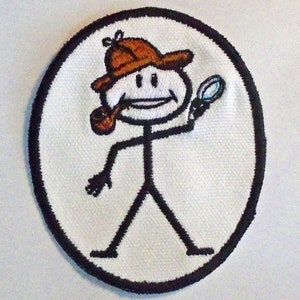 May include: A white embroidered patch with a black outline, featuring a stick figure wearing a brown hat, holding a magnifying glass and a pipe.