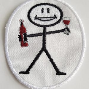 Peut inclure: Patch brodé blanc avec un bonhomme tenant une bouteille de vin et un verre de vin. Le bonhomme a un visage souriant.