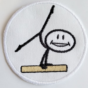 Puede incluir: Un parche bordado blanco y circular con un muñeco de palo sonriente realizando una rutina de gimnasia en una barra de equilibrio. El muñeco de palo es negro y la barra es marrón. El parche tiene un borde blanco.