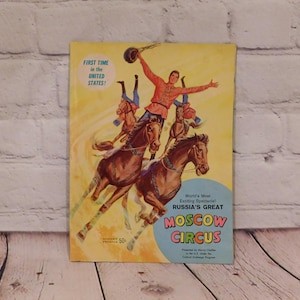 May include: Vintage Moscow Circus program cover. The cover features a vibrant illustration of circus performers on horseback. The text reads "First Time in the United States!" and "World's Most Exciting Spectacle! Russia's Great Moscow Circus."
