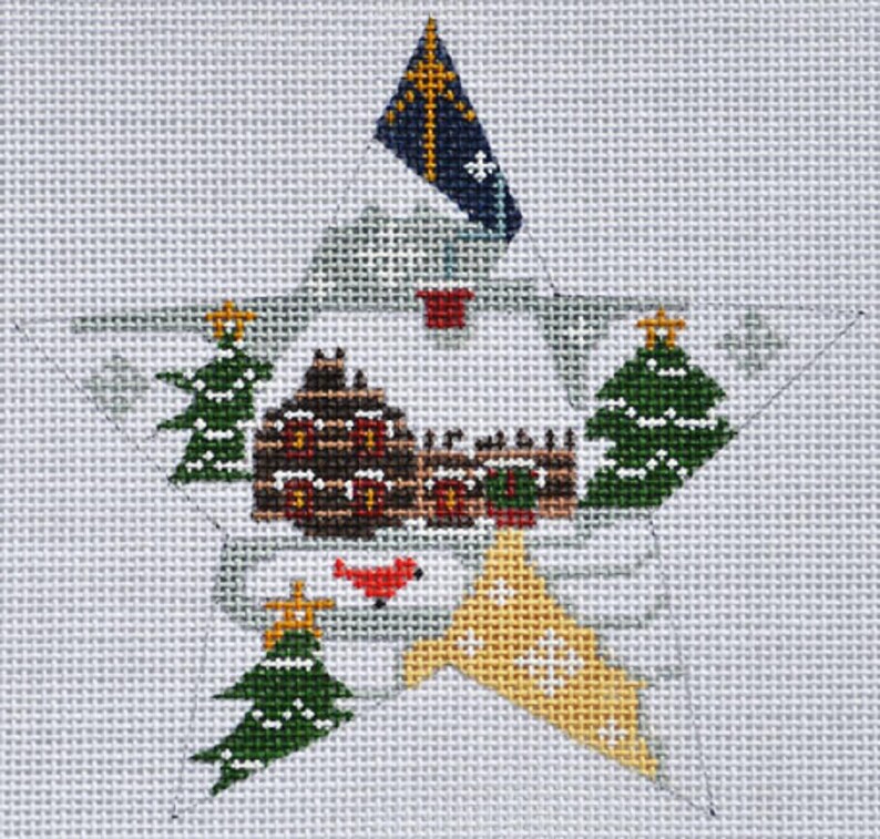 Puede incluir: Dise&ntilde;o de estrella navide&ntilde;a cosido a mano sobre lienzo. La estrella presenta una casa marr&oacute;n con detalles en rojo, &aacute;rboles de Navidad verdes y una bandera amarilla y azul. El dise&ntilde;o est&aacute; sobre un fondo gris claro.