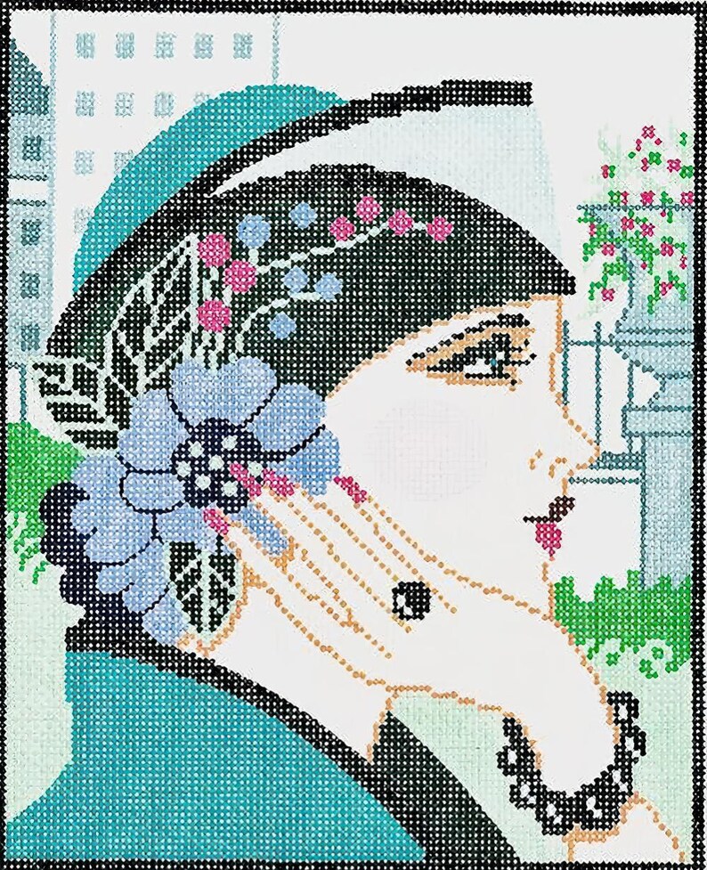 May include: Needlepoint art of a woman in profile, wearing a black hat adorned with pink and blue floral accents. She holds a blue flower, with a black beaded necklace. The background features a cityscape and floral elements.